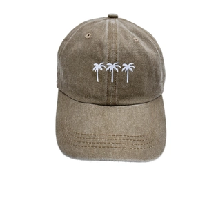 Close-up of white palm tree embroidery on a vintage washed brown cotton baseball cap
