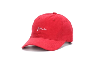 Close-up of a red cotton baseball cap featuring white 'me' script embroidery on the front
