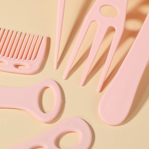 Set of 6 pink plastic hair combs and styling tools professionally displayed on beige background