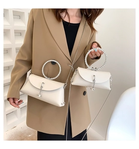 Detail of elegant cream shoulder bag featuring a sparkling rhinestone ring handle and chain