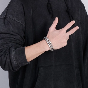 Close-up of thick silver Cuban link bracelet for men on wrist with black hoodie