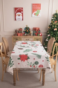 Detailed view of Christmas tablecloth with floral festive print and tassel edges on wood table