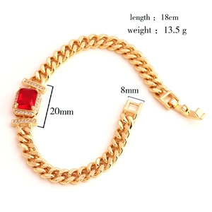 Macro view of gold Cuban link bracelet featuring a large rectangular red zircon and diamonds