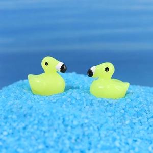 Macro shot of two miniature yellow resin ducks on blue sand for DIY bonsai landscaping