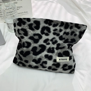 Detail der grauen Kosmetiktasche mit Leopardenmuster, ATRYG-Etikett und Canvas-Struktur