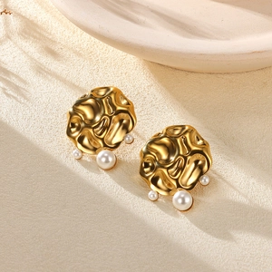 Macro shot of gold-tone starfish earrings with pearl details and hand-hammered texture
