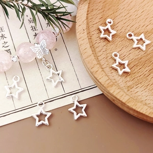 Macro detail of silver star alloy pendants and pink crystal bead DIY bracelet on wood