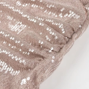 Close-up detail of pink sequin fabric with sparkling glitter texture and pleated pattern