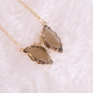 Detail of golden butterfly necklace with amber crystals and diamonds on white fur
