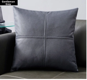 Detail of dark gray tech fabric pillowcase featuring a cross-stitch seam on a leather sofa