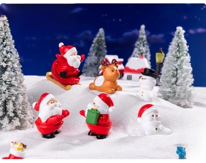 Miniature resin Santa, reindeer, and snowman figurines in a snowy Christmas landscape