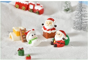 Close-up of resin Christmas miniatures with snowman and Santa on artificial snow