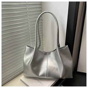 Detailed close-up of metallic silver tote bag texture with natural folds on a white book