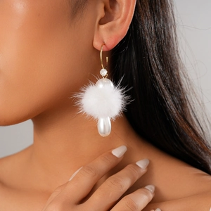 Detail of C-shaped drop earring with white pompom and pear-shaped pearl on model
