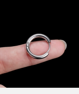 Close-up of polished silver stainless steel hoop earring held between fingers for size