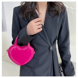 Mini heart-shaped fuchsia patent leather crossbody bag shown on a black suit model