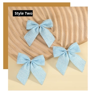 Close-up of three light blue faux linen bows with silver bead on a wooden surface