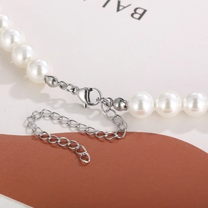 Macro detail of pearl necklace showing the silver lobster clasp and adjustable metal chain