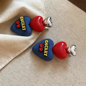 Macro shot of heart-shaped hair clips featuring blue denim, red enamel and silver metal finish