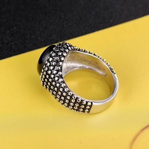 Macro view of vintage stainless steel men's ring with black oval gemstone and bead texture