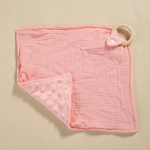 Vista detallada de una mantita de apego rosa para bebé con texturas de muselina y minky