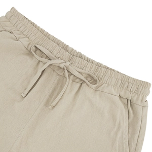 Detail of men's linen shorts showing elastic waistband and beige drawstring texture