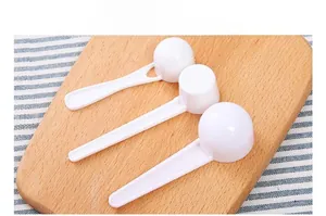 Detail view of smooth white plastic measuring spoons on a wooden board and tablecloth
