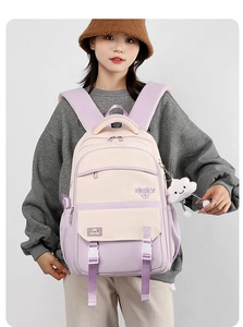 Detail of purple and beige student backpack with cloud charm on model's back