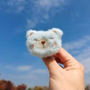 Close-up of light blue plush bear hair accessory against a clear blue sky background