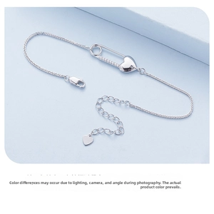 Detail of S925 silver heart bracelet with zircon-studded safety pin and wheat chain