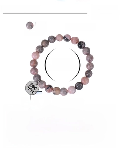 Détail des perles en pierre zèbre rose et charm en acier gravé Dog Mom sur le bracelet