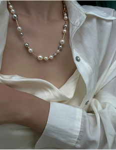 Macro shot of colorful high-luster pearls on a delicate gold chain over white silk fabric