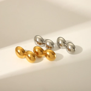 Gros plan détaillé de boucles d'oreilles en forme de haricot en acier doré et argenté poli