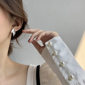 Detail shot of elegant gold leaf earrings with shell inlay worn by a female model
