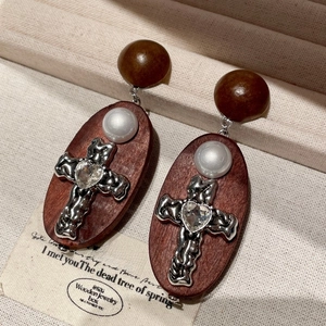 Détail de boucles d'oreilles vintage en bois avec croix métallique et strass cœur