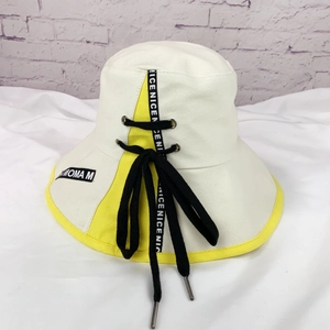 Détail du chapeau bob crème avec bordure jaune et sangles décoratives noires