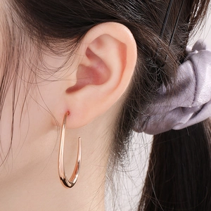 Close-up of a model wearing a rose gold U-shaped polished stainless steel earring