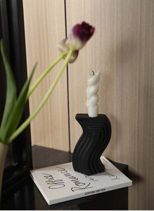 Detail of matte black wave ceramic base with white spiral scented candle decor