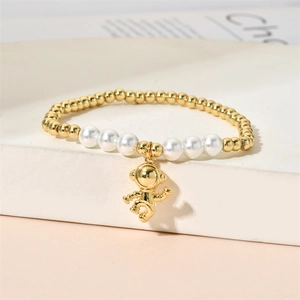 Detail of beaded bracelet featuring gold astronaut charm with white faux pearls