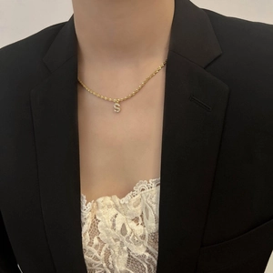 Détail du collier pendentif lettre S étincelant avec cristaux sur chaîne dorée