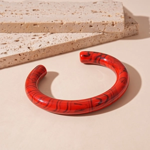 Detailed close-up of a red marble-patterned acrylic open bangle on stone plates