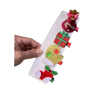 Détail d'un lot de 4 pinces à cheveux de Noël avec sapin scintillant, cadeau et gant
