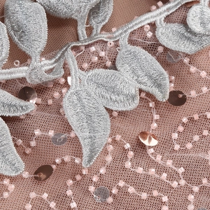Detailed embroidery and sequins on rose pink mesh fabric of a formal evening dress