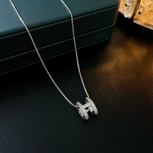 Macro detail of silver H pendant with pavé zircons on a classic box chain necklace