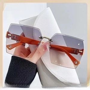 Detail of rimless gradient sunglasses with purple lenses and brown temples on a white case