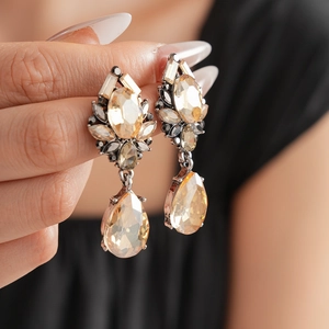 Detailed view of vintage teardrop earrings with champagne crystals held by a hand