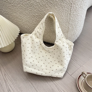 Close-up of beige corduroy tote bag with brown floral pattern and ribbed texture detail