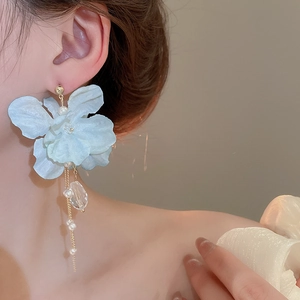 Close-up of light blue fabric flower earrings with long pearl and crystal tassels