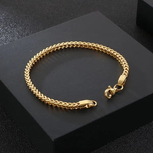 Detail view of a gold-plated stainless steel wheat chain bracelet with a lobster clasp