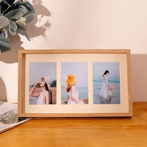 Three-window natural wood photo frame with beige matting on a cozy wooden desk